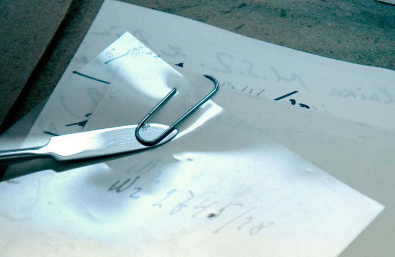 Sposób usuwania metalowego spinacza. Pod spinacz wsunięto pasek z materiału chroniącego papier przed narzędziem. W tym przypadku użyto pasek melineksu (zdj. M. Wiercińska)